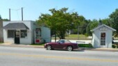 <b>2nd Smallest Police Station - </b>I doubt that anyone noticed the two small white buildings just up the street from where we ate, but I did. Here is a photo from a couple of years ago when Donna and I visited town taking Post Office pictures. The building on the right is billed as the World?s Smallest Police Station on RoadsideAmerica.com. When the town outgrew the tiny building in 1990 by adding a second officer they moved into a much larger place...the building on the left. 2nd Smallest Police Station