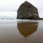 <b>Haystack Rock Reflection - </b>Haystack Rock, a 235-foot tall sea stack, the third-tallest such structure in the world (behind a couple in Scotland I think) is reflected in the wet sand. (10/02/06) Haystack Rock Reflection